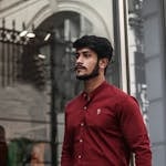 Handsome young man in stylish urban outfit walking confidently on city street photoshoot outdoors.