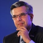 Portrait of a thoughtful businessman in a suit, wearing eyeglasses, captured in an indoor corporate setting.
